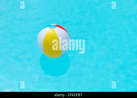 Beach Ball schwimmend auf der Wasseroberfläche eines Schwimmbades. Sommerhintergrund. Speicherplatz kopieren Stockfoto
