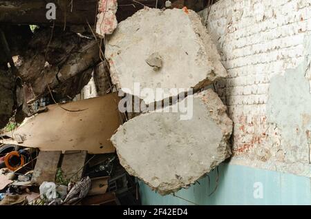 Zerbrochene Betonplatte aus der Nähe, fiel beim Zerlegen eines großen Betongebäudes. Stücke von Betonplatten hängen von der Bewehrung. Gefahr conce Stockfoto