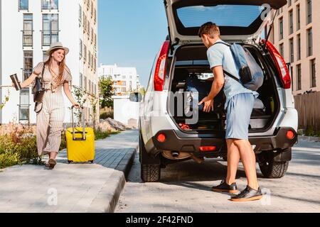 Paar sammeln für Road Trip. Putting Taschen auf Auto-Kofferraum. Sommerferien Stockfoto