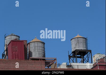 Wassertanks auf dem Dach eines Wohnhauses in New york Vor einem klaren blauen Himmel mit Kopierraum Stockfoto