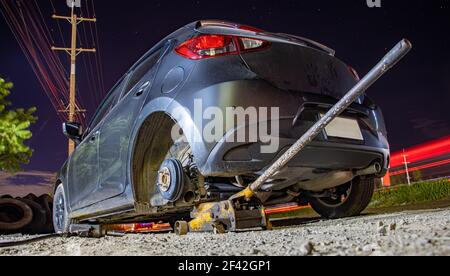 Nachtschaltung in der Werkstatt auf der Autobahn. Austausch eines beschädigten Rades mit Hilfe eines hydraulischen Wagenhebers. Stockfoto