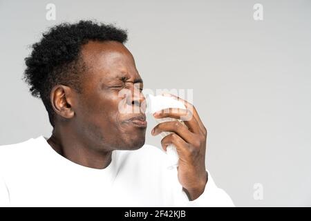 Schwarzer Mann bläst Nase und niesen in Gewebe oder Serviette, hat Allergie, erste Symptome von Erkältung und Grippe Stockfoto