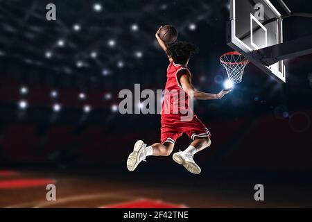 Basketball-Spieler in roten Uniform springen hoch, um eine zu machen slam Dunk in den Korb Stockfoto