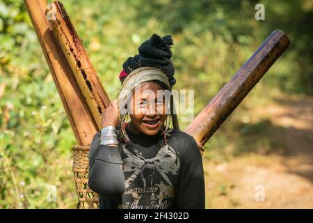 Porträt einer erwachsenen Frau des Stammes der Engstämme, die Bambusstämme im Packkorb trägt, in der Nähe von Kengtung, Myanmar Stockfoto