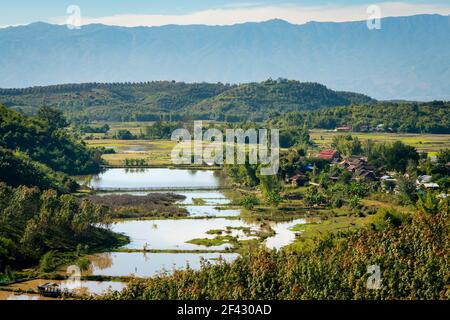 Landschaftlich schöner Blick auf abgelegenes Dorf neben überschwemmtem Reisfeld, in der Nähe von Kengtung, Myanmar Stockfoto