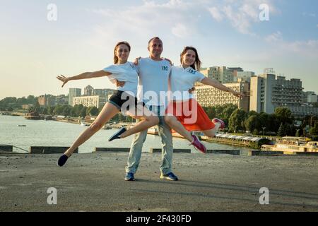 Dnepropetrovsk, Ukraine - 08,09.2017: Fröhliche Städter tanzen auf dem Platz in der Stadt bei Sonnenaufgang. Ein junger Mann und zwei Mädchen tanzen gerne. Stockfoto