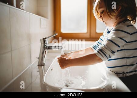 Seitenansicht des jungen Kindes im Alter von Vorschulalter, das sich Hände wäscht Seife Stockfoto