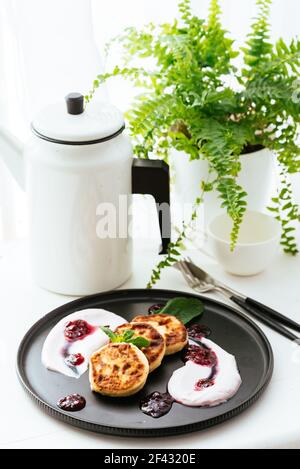 Käsepfannkuchen mit Marmelade auf schwarzem Teller Stockfoto