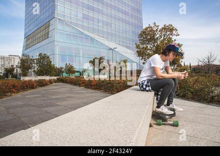 Frau mit Mütze sitzend mit Skateboard Stockfoto