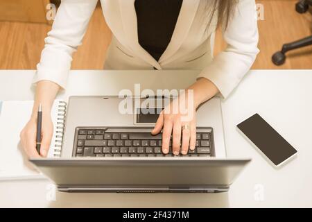Aufgenommen von oben mit Frau, die mit Laptop und Handy arbeitet Stockfoto
