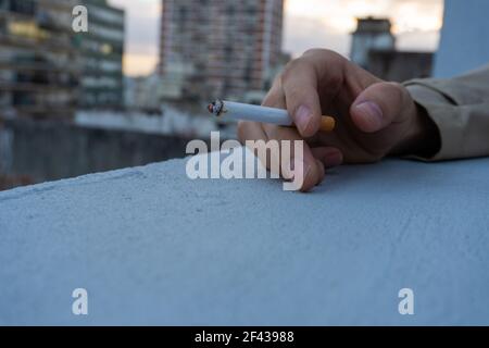 Hand eines Mannes Rauchen Zigarette oder Tabak. Schlechte Gewohnheiten. Schlechteste Gewohnheiten. Rauchen aufhören Konzept. Gesundheitsschädlich. Mai 31. Blick auf die Stadt Stockfoto