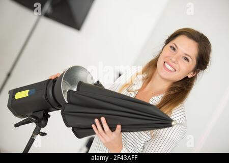 Junger kreativer Fotograf, der das Licht im Studio kontrolliert Stockfoto