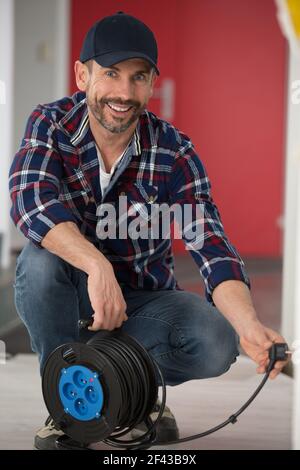 Mann, der ein Verlängerungskabel an einer Spule einsteckt Stockfoto