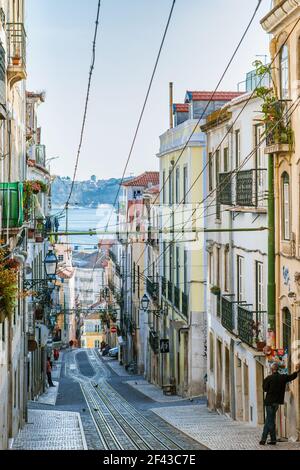 Rua da Bica de Duarte Belo, berühmt für seine ikonische gelbe Standseilbahn (Elevador Da Bica) im historischen Zentrum von Lissabon, Portugal. Stockfoto