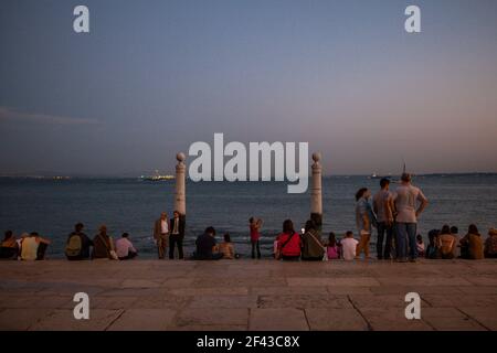 Touristen, die den Sonnenuntergang am Pier von Cais das Colunas genießen, am Ufer des Flusses Tejo in Praça do Comércio, im Zentrum von Lissabon, Portugal Stockfoto