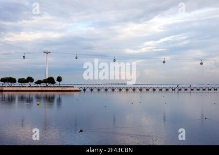 Die Seilbahnen, die über den Tejo Fluss im Parque das Naçoes in Expo fliegen, mit der Vasco de Gama Brücke im Hintergrund - Lissabon, Portugal Stockfoto