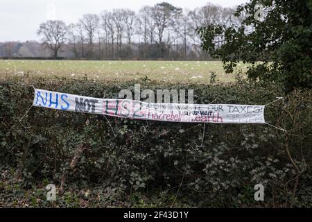 Great Missenden, Großbritannien. März 2021, 18th. Ein Banner, das Investitionen in den NHS statt HS2 fordert, ist in der Nähe von Werken abgebildet, um eine Reihe von hundert Jahre alten Eichen in Leather Lane fiel. Fast 40.000 Menschen haben vor kurzem eine Petition unterzeichnet, in der gefordert wird, dass die Bäume, die die alte Landstraße säumen, nicht gefällt werden, um Platz für eine temporäre Haul-Straße und eine Baustelle zu schaffen.Anwohner und Naturschützer haben HS2 Auftragnehmer beschuldigt, aktive Vogelkisten auf dem Gelände zu zerstören. Kredit: Mark Kerrison/Alamy Live Nachrichten Stockfoto