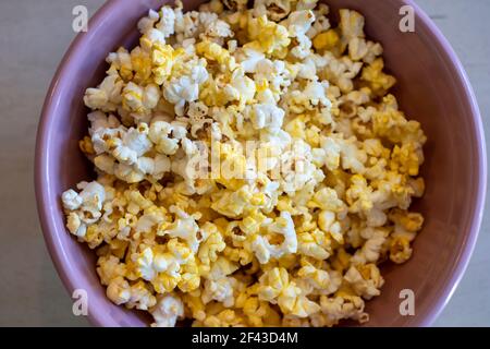 Popcorn, oder poppte Mais, in einer rosa Schüssel auf einem Tisch. Stockfoto