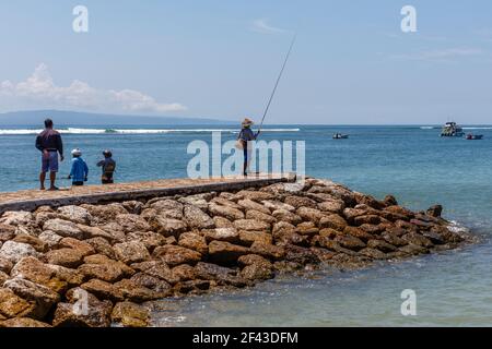 Indonesische Fischer mit Angelruten am Strand von Sanur, Bali, Indonesien. Stockfoto