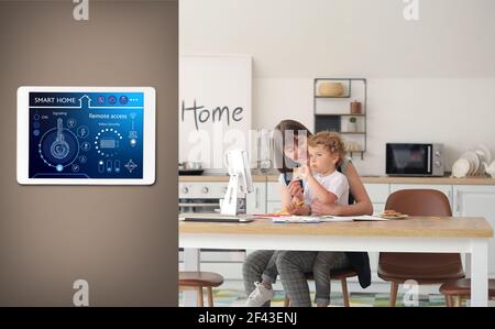 Glückliche junge Mutter mit kleinen Sohn in der Küche unter Schutz Smart Home Sicherheitssystem Stockfoto