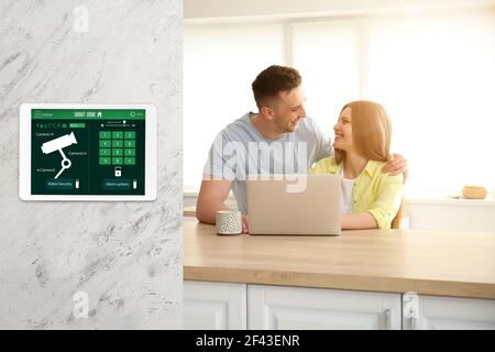 Glückliches junges Paar in der Küche unter dem Schutz der Smart Home Sicherheitssystem Stockfoto