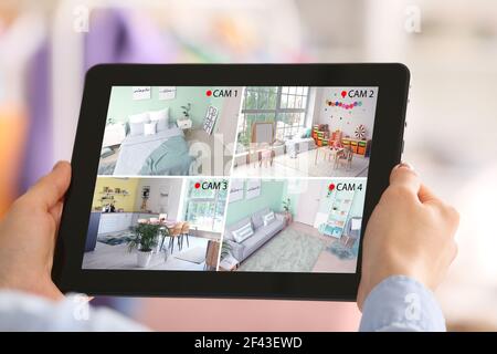 Frau mit Tablet-Computer Blick auf die Bilder von cctv Kameras in der Wohnung installiert Stockfoto