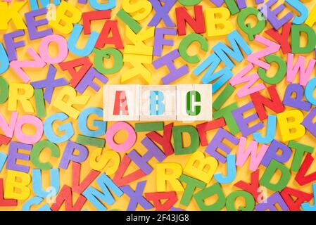 Alphabet auf Holzfliesen und ABC auf einem Würfel vor gelbem Hintergrund. Konzept der Entwicklung der Bildung von Kindern Stockfoto
