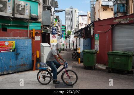 10,03.2021, Singapur, Republik Singapur, Asien - EIN Mann mit Gesichtsmaske radelt durch eine enge Seitenstraße im Stadtteil Little India. Stockfoto