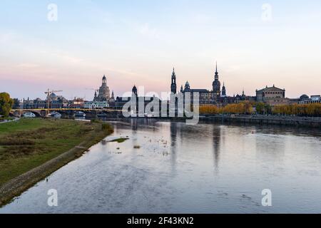 Dresdner Stadtsilhouette an der Elbe in der Herbstsaison. Schöne bunte Blätter bei Sonnenuntergang Abend. Reflexionen im Wasser dieser Landschaft. Stockfoto