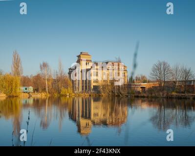 Alte verlassene Porzellanfabrik in Abendsonne bei Sonnenuntergang. Reflexionen im Wasser des Gebäudes sehen wunderschön aus. Stockfoto