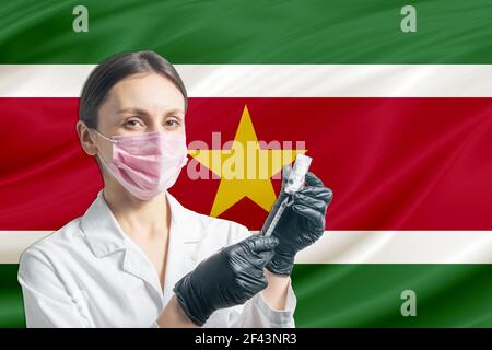 Ärztin bereitet die Impfung vor dem Hintergrund der Suriname-Flagge vor. Impfkonzept Surinam. Stockfoto
