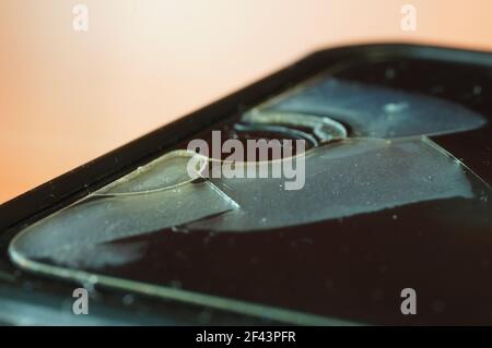 Smartphone-Schutzglas – beschädigt, gerissen, abgenutzt. Alter Bildschirmschutz. Schmutziges, schwarzes, abgenutztes Telefon. Stockfoto
