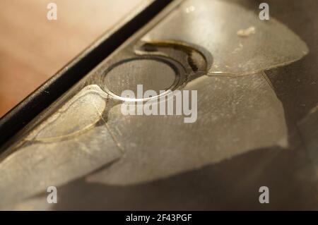 Smartphone-Schutzglas – beschädigt, gerissen, abgenutzt. Alter Bildschirmschutz. Schmutziges, schwarzes, abgenutztes Telefon. id-Taste. Stockfoto