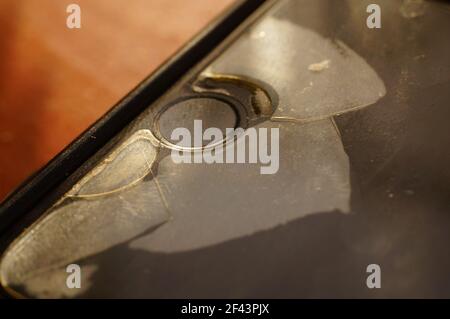 Smartphone-Schutzglas – beschädigt, gerissen, abgenutzt. Alter Bildschirmschutz. Schmutziges, schwarzes, abgenutztes Telefon. Stockfoto