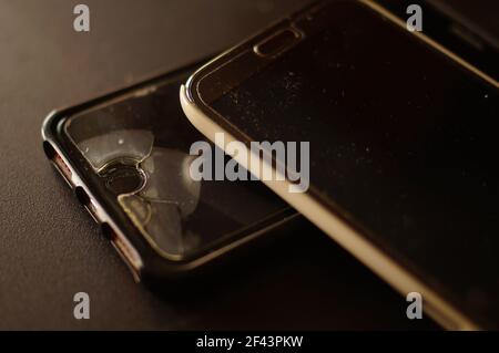 Zwei gebrauchte große schwarze Handys. LCD-Schutzfolie mit Gebrauchsspuren. Zerstörung und Verschleiß auf dem Bildschirm. Telefone, die Service benötigen. Stockfoto