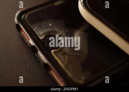 Smartphone-Schutzglas – beschädigt, gerissen, abgenutzt. Alter Bildschirmschutz. Schmutziges, schwarzes, abgenutztes Telefon. Stockfoto