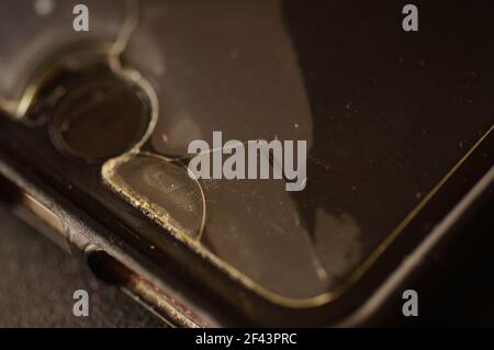 Smartphone-Schutzglas – beschädigt, gerissen, abgenutzt. Alter Bildschirmschutz. Schmutziges, schwarzes, abgenutztes Telefon. Stockfoto