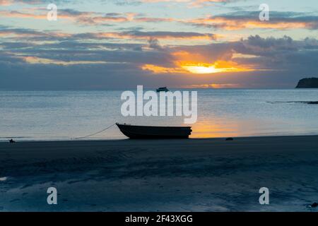 Silhouette eines Schlauchbootes am Ufer bei Ebbe am Mulberry Grove Beach Great Barrier Island, Neuseeland. Stockfoto