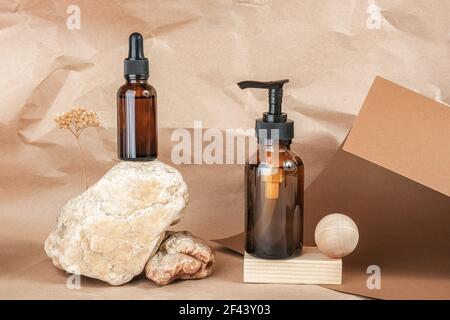 Braune Glasflaschen von kosmetischen Produkten auf Stein und hölzernen geometrischen Formen auf beige Handwerk Papier Hintergrund. Natürliche organische Spa kosmetische Schönheit con Stockfoto