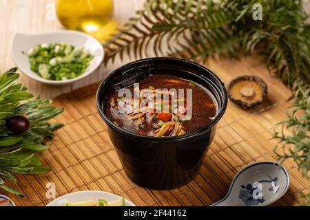 Nehmen Sie Nudelsuppe mit Huhn und Gemüse in Kunststoff Schwarze Schale Stockfoto