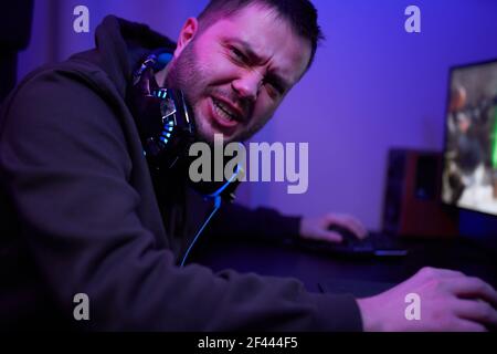 Gamer oder Streamer in Kopfhörern mit Mikrofon sitzt zu Hause Und spielt am pc Stockfoto
