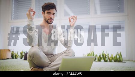 Bleiben Sie sicher Text über Mann Yoga üben und mit Laptop Stockfoto