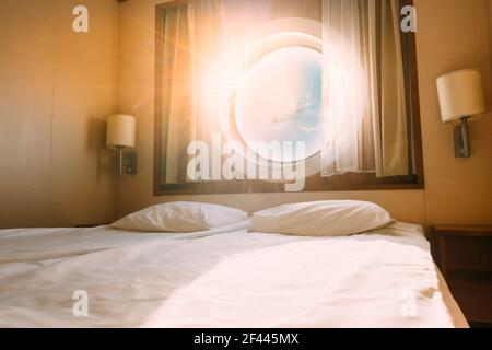 Natürliches Sonnenlicht Leuchtend Durch Schiffsfenster In Craft Cabin Mit Bett. Blick Auf Das Meer. Luxuskabine Auf Dem Fährboot Oder Kreuzfahrtschiff. Seekreuzfahrt Urlaub Stockfoto