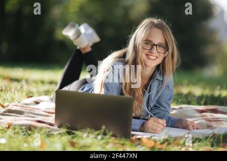 Hübsche Frau mit Laptop für das Studium im Park Stockfoto