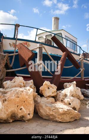 Anker und Felsen neben dem Boot am Eingang von Popeye's Village in Malta. Stockfoto