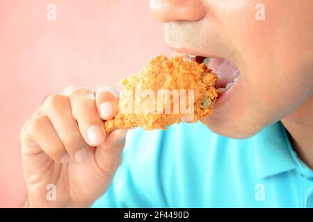 Ein Mann beißt frittiertes Hühnerbein oder Drumstick Stockfoto