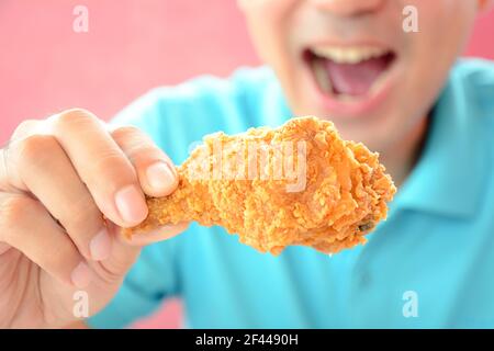 Ein Mann mit Öffnung Mund über frittierte essen Hühnerbein oder Drumstick Stockfoto