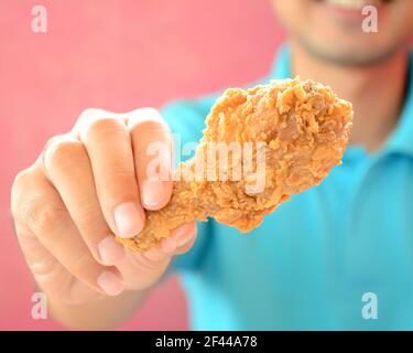 Ein Mann, der gebratenes Hühnerbein oder einen Drumstick gab Stockfoto