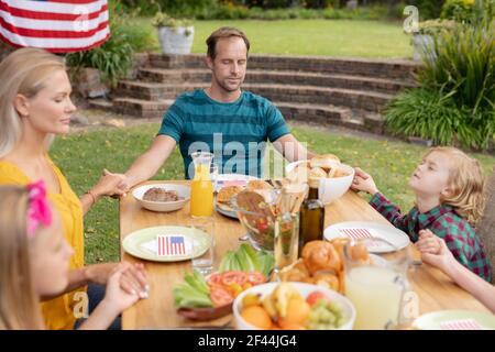 Kaukasischer Mann und Familie halten Hände sagen Gnade vor dem Essen Gemeinsames Essen im Garten Stockfoto