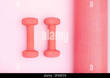 Pinke Übungsmatten in der Mitte des hellen Hintergrunds mit Frauen Fitness Yoga Matte. Minimales künstlerisches Konzept. Stockfoto